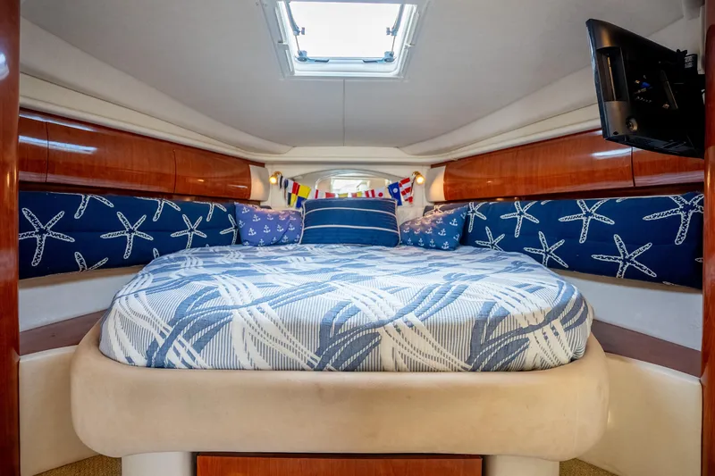 Slide: The Image of 2003 Sea Ray 360 Sundancer cabin with nautical-themed bedding and wood paneling. - 26
