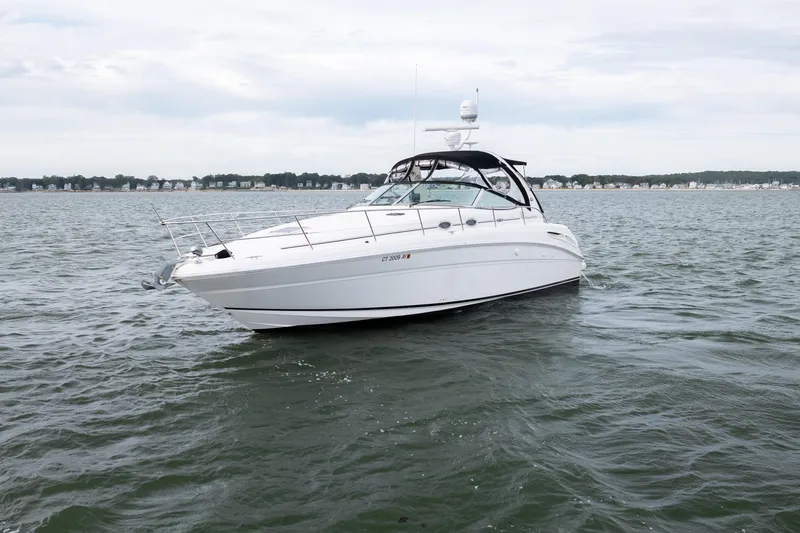 Slide: The Image of 2003 Sea Ray 360 Sundancer yacht on calm waters with distant shoreline. - 8