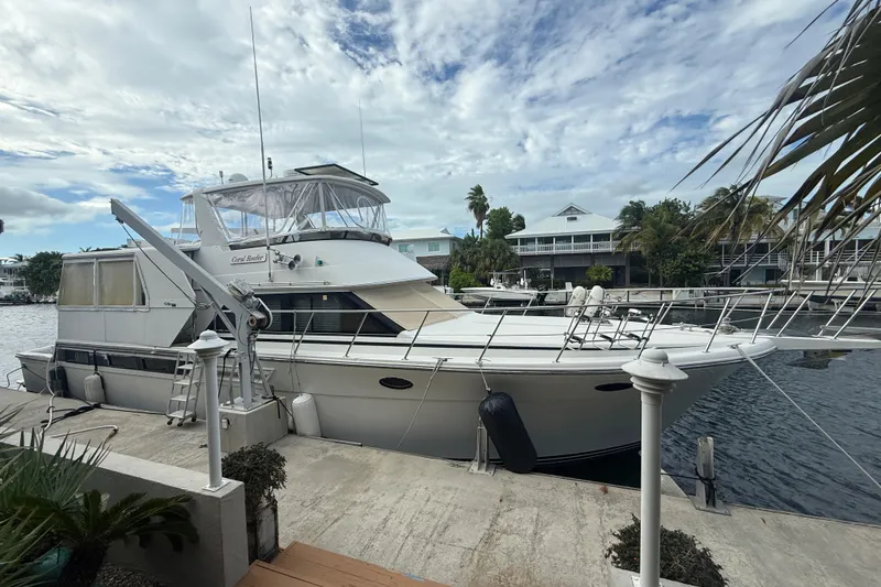 Slide: The Image of 1991 Californian 55 Cockpit Motor Yacht docked by waterfront homes under a cloudy sky. - 20