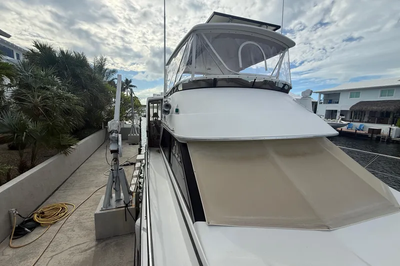 Slide: The Image of 1991 Californian 55 Cockpit Motor Yacht docked by waterfront homes under cloudy sky. - 46