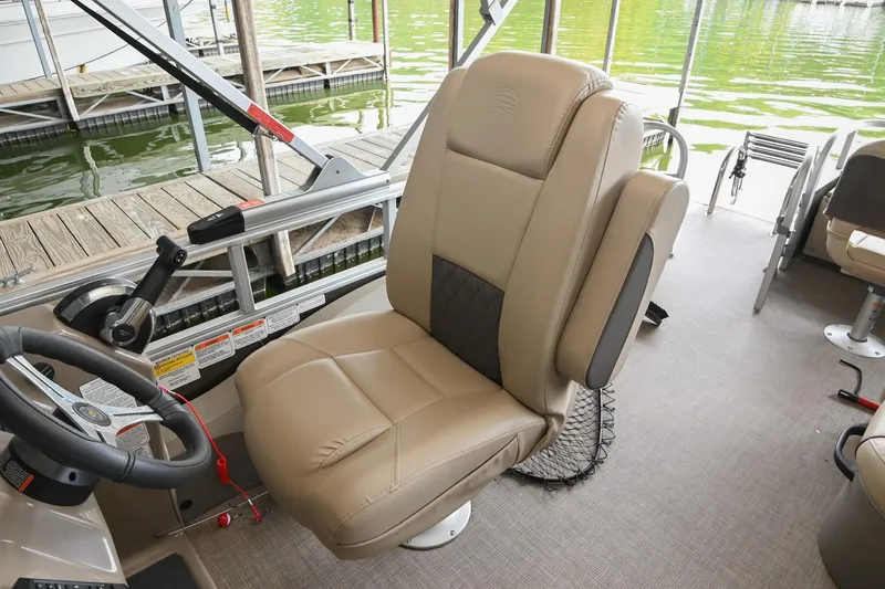 Slide: The Image of 2023 SUNTRACKER DLX 22 Sportfish boat interior with beige captain's chair and steering wheel. - 18