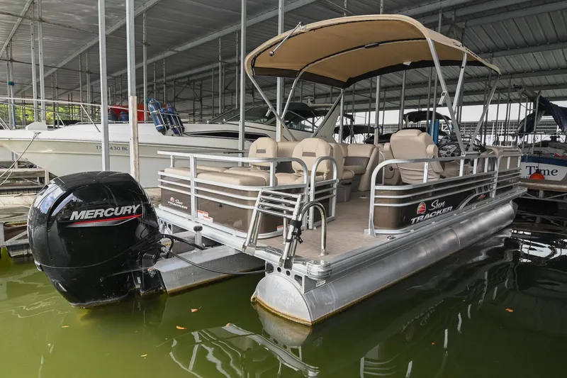 Slide: The Image of 2023 SUNTRACKER DLX 22 Sportfish pontoon boat with Mercury engine docked in marina. - 2