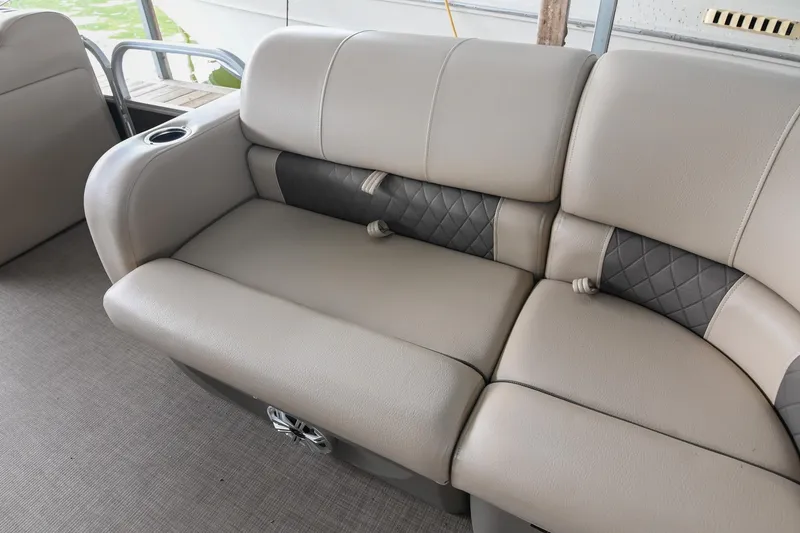Slide: The Image of 2023 SUNTRACKER DLX 22 Sportfish boat interior with beige cushioned seating and cup holder. - 21