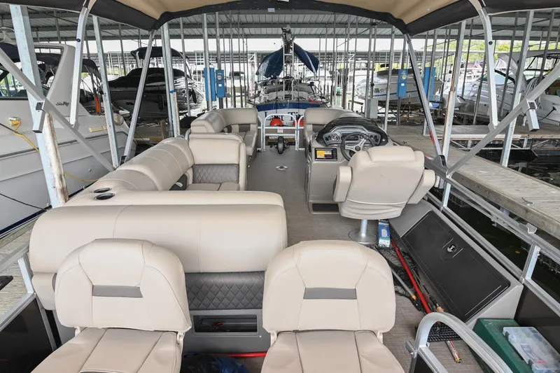 Slide: The Image of 2023 SUNTRACKER DLX 22 Sportfish pontoon boat interior with beige seating and steering console. - 4