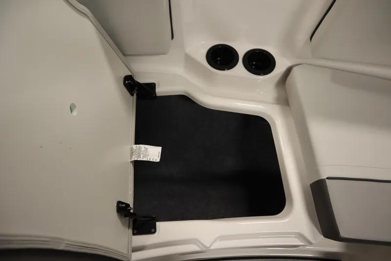 Slide: The Image of 2026 Yamaha Boats SX220 interior storage compartment with open hatch and cup holders. - 14