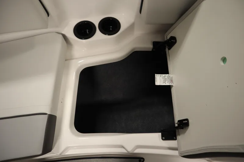 Slide: The Image of 2026 Yamaha Boats SX220 interior storage compartment with open hatch and cup holders. - 16