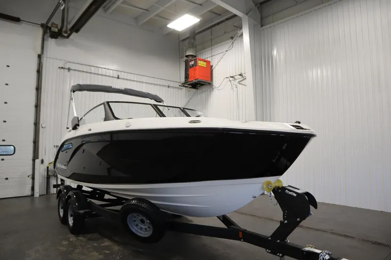 Slide: The Image of 2026 Yamaha Boats SX220 in a showroom, sleek black and white design on a trailer. - 2