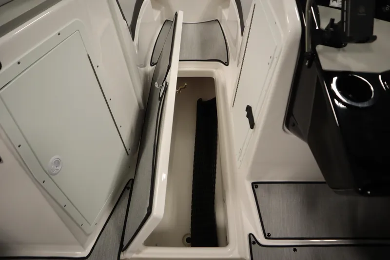 Slide: The Image of 2026 Yamaha Boats SX220 interior storage compartment, open with visible black mat. - 28