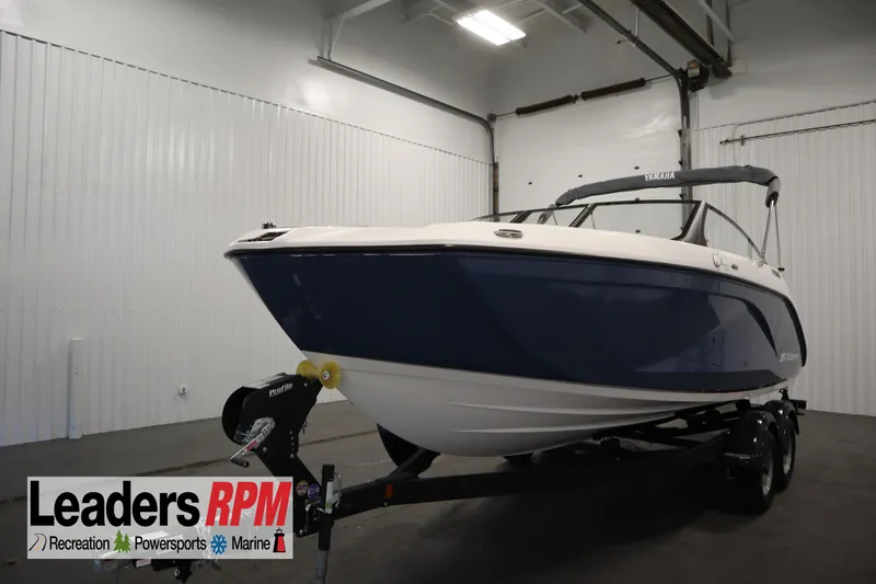 The Image of 2026 Yamaha Boats SX220 in showroom, blue and white design, on trailer. - 0