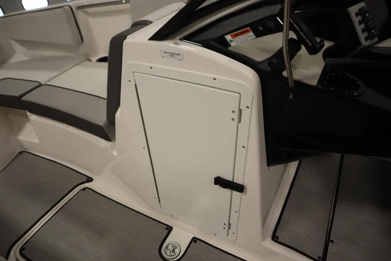 Slide: The Image of 2026 Yamaha Boats SX220 storage compartment with open hatch and cup holders. - 17