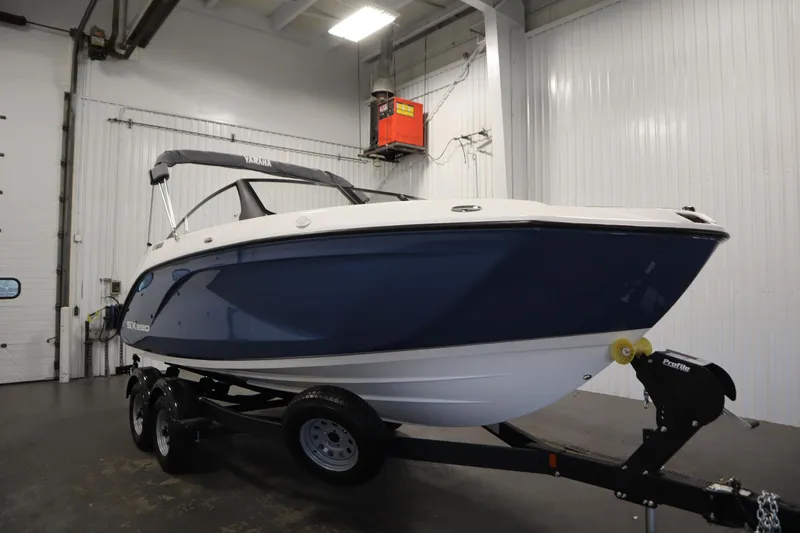 Slide: The Image of 2026 Yamaha Boats SX220 in showroom, blue and white design on trailer. - 2