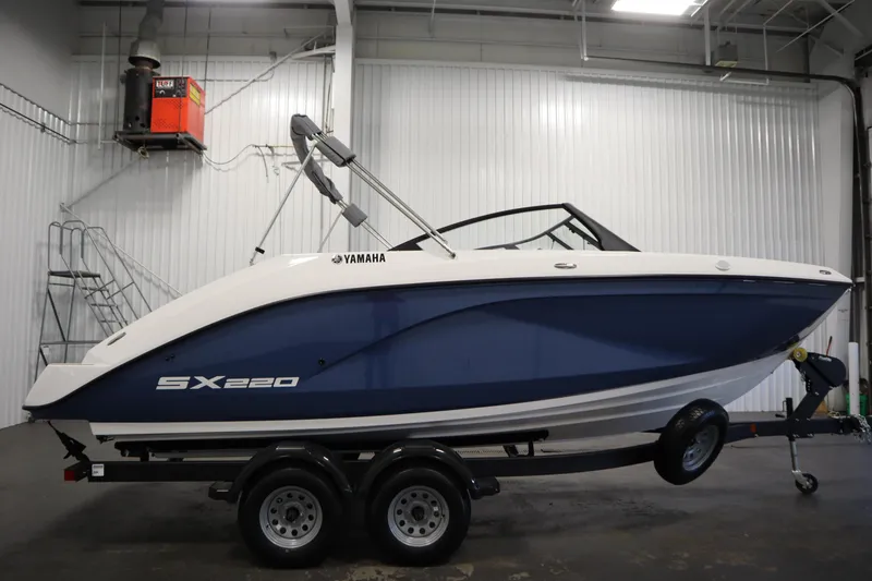 Slide: The Image of 2026 Yamaha Boats SX220 in a garage, blue and white hull on a trailer. - 3