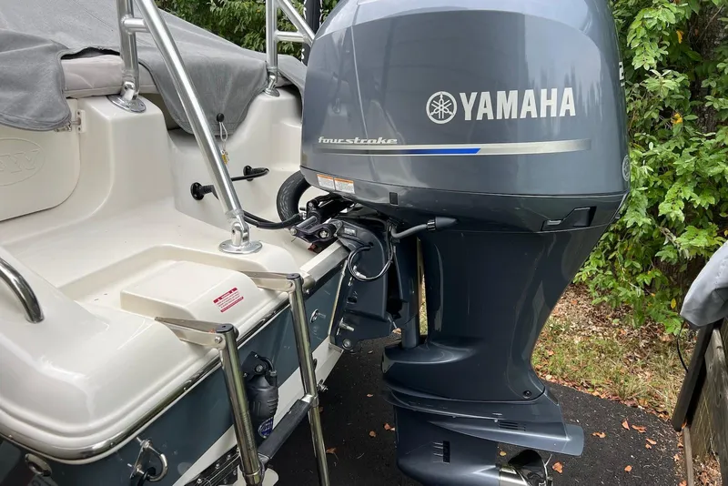Slide: The Image of 2022 Key West 203 DFS boat with Yamaha four-stroke outboard motor, parked near greenery. - 11