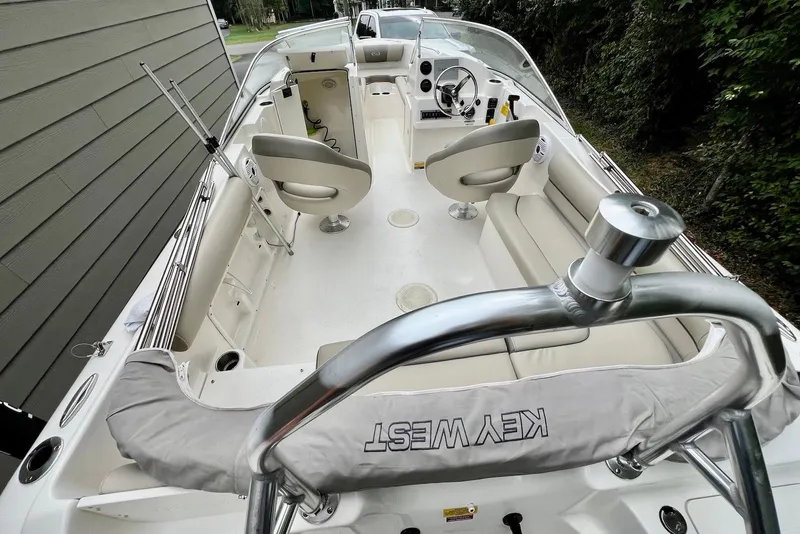 Slide: The Image of 2022 Key West 203 DFS boat interior with seating and steering wheel, parked near trees. - 6