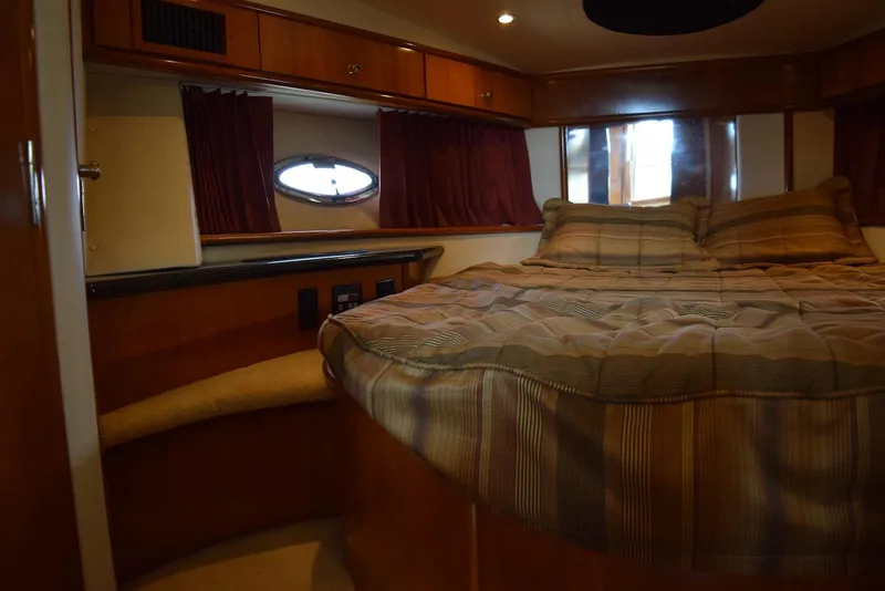 Slide: The Image of Cozy bedroom in 2001 Carver 444 Cockpit Motor Yacht with wood accents and porthole window. - 29