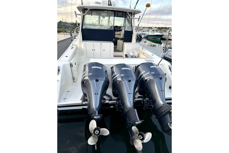 Slide: The Image of 2014 PURSUITE 385 boat with triple Yamaha outboard engines docked at marina. - 2