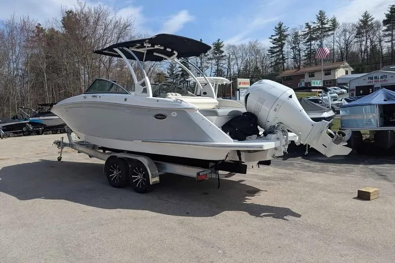 Slide: The Image of 2020 Cobalt 25SC boat on trailer, parked outdoors with trees in background. - 2