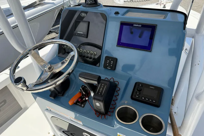 Slide: The Image of 2023 Sea Pro 228 Bay boat dashboard with steering wheel, controls, and navigation display. - 12