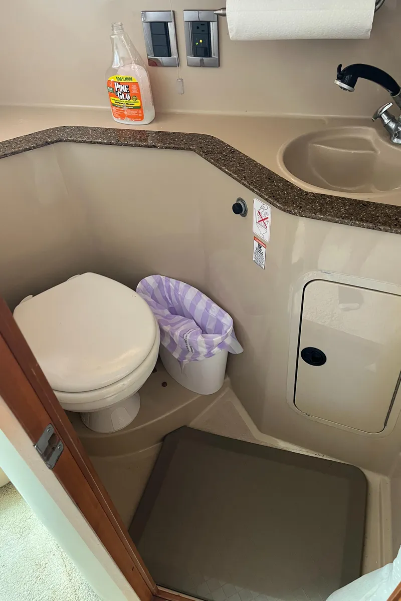 Slide: The Image of 2001 Cruisers Yachts 2870 Express bathroom with toilet, sink, and cleaning supplies. - 31