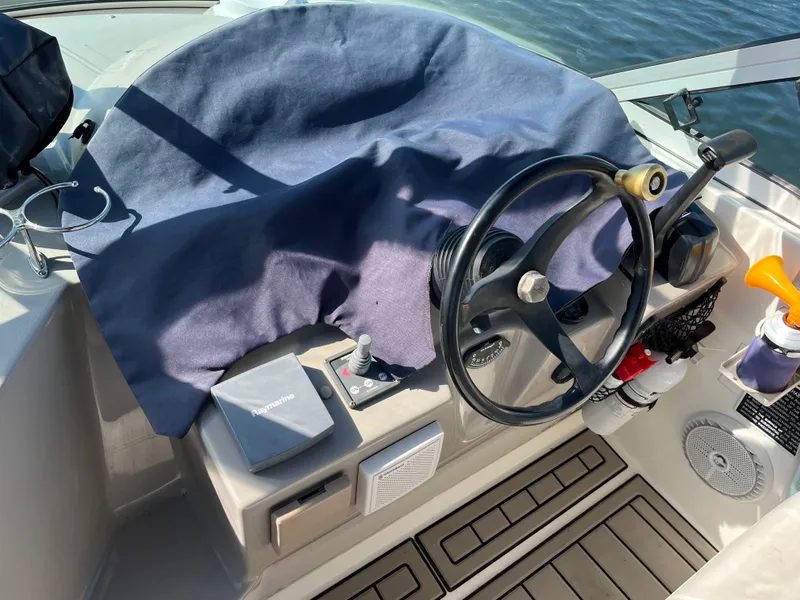Slide: The Image of 2001 Cruisers Yachts 2870 Express helm with steering wheel and controls, covered in blue fabric. - 11