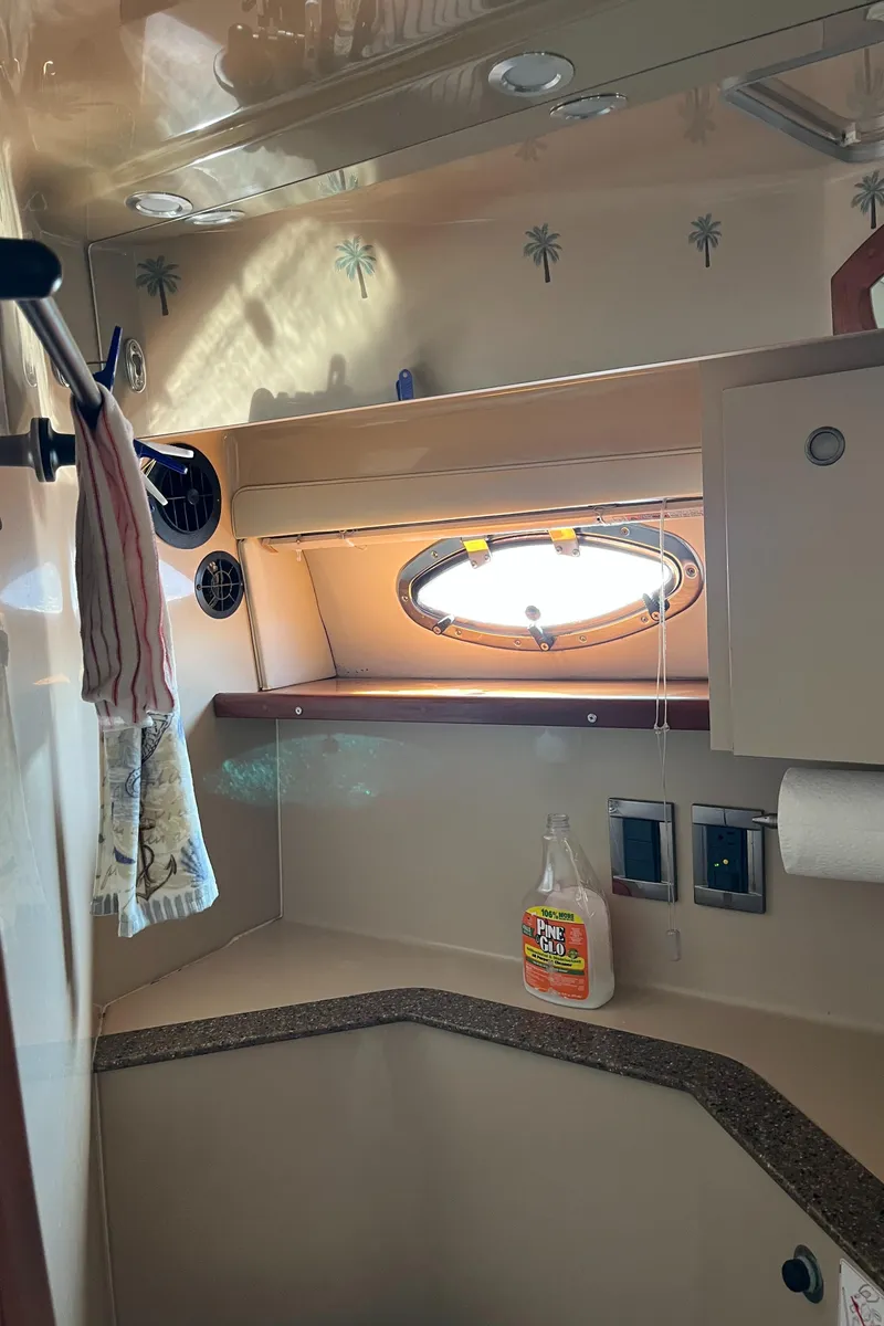 Slide: The Image of 2001 Cruisers Yachts 2870 Express cabin interior with porthole and cleaning supplies. - 33