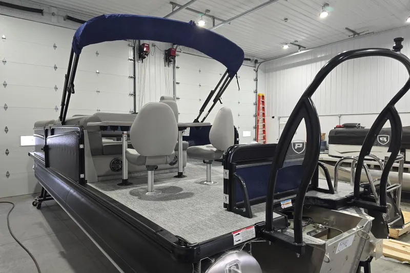 Slide: The Image of 2025 Premier 250 Sunsation RS pontoon boat in a garage, featuring seating and canopy. - 11