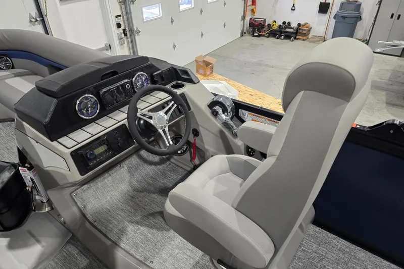 Slide: The Image of 2025 Premier 250 Sunsation RS boat interior with steering wheel and captain's chair in a garage. - 15