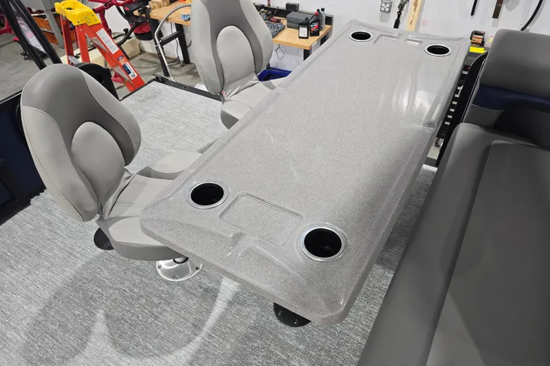 Slide: The Image of 2025 Premier 250 Sunsation RS boat interior with gray seating and table featuring cup holders. - 23
