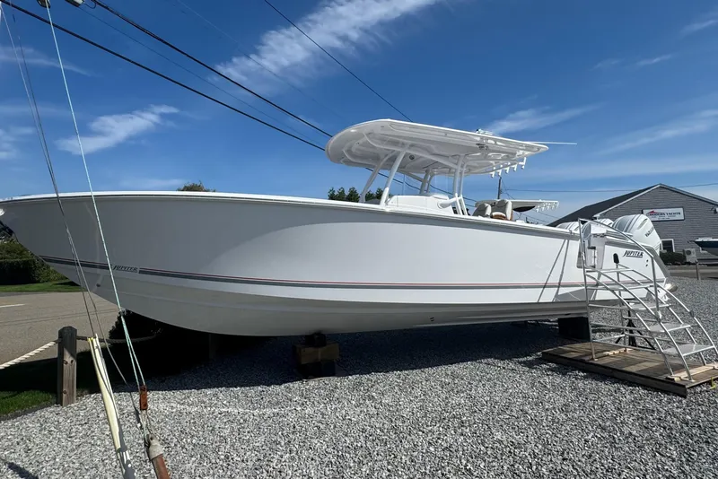 Slide: The Image of 2026 Jupiter 34 boat displayed outdoors on gravel, under a clear blue sky. - 2