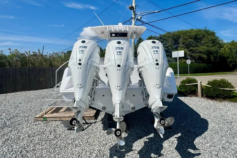 Slide: The Image of Triple 350 V6 outboard engines on a 2026 Jupiter 34 boat, parked on gravel. - 4