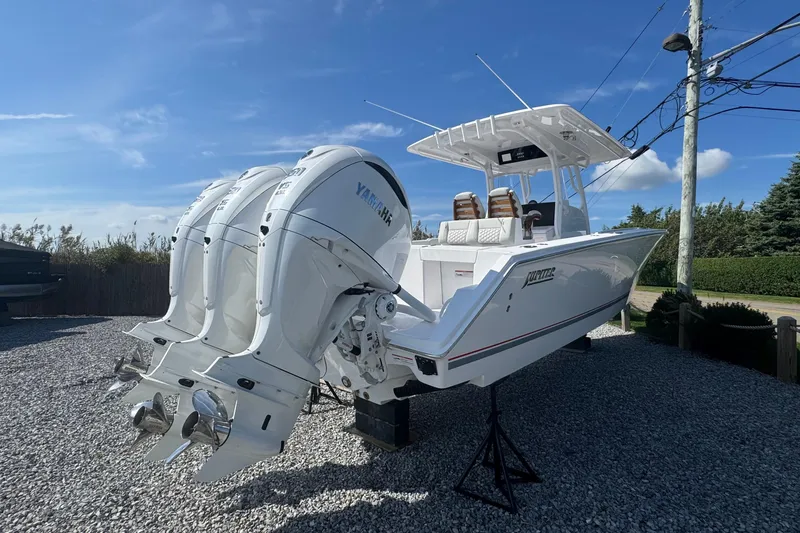 Slide: The Image of 2026 Jupiter 34 boat with triple Yamaha outboard engines on gravel lot. - 5