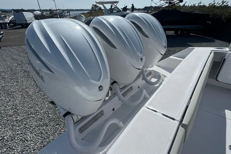 Slide: The Image of Triple outboard engines on a 2026 Jupiter 34 boat, docked on gravel. - 6