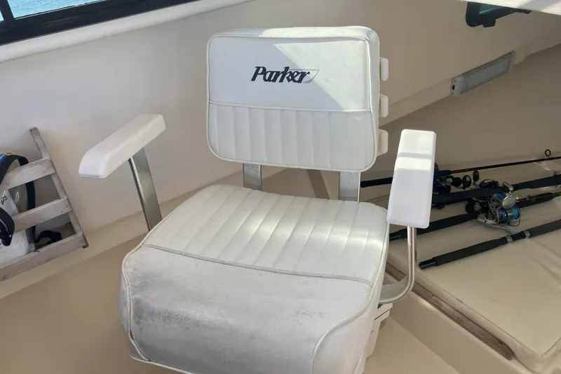 Slide: The Image of White captain's chair on 2001 Parker 2520 Sport Cabin boat, with fishing rods nearby. - 13