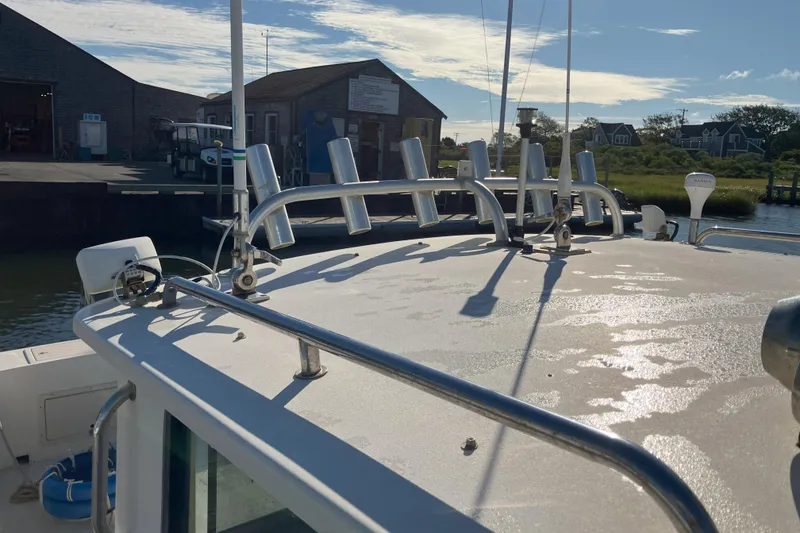 Slide: The Image of 2001 Parker 2520 Sport Cabin boat docked, featuring rod holders and antennas under a clear sky. - 8