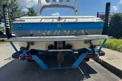 Slide: The Image of 2004 Supra Launch SS boat on trailer, blue and white design, parked outdoors. - 3