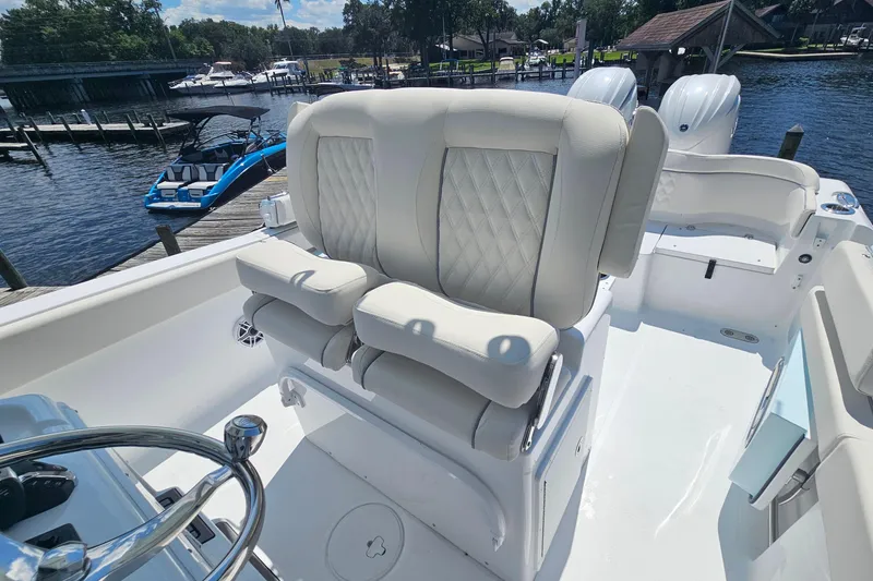 Slide: The Image of 2026 Sea Hunt Ultra 265 SE boat with luxurious seating and dual engines at a marina. - 11