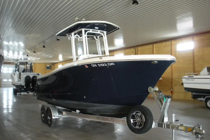 The Image of 2025 Robalo R230 Center Console boat on trailer in indoor storage facility. - 0