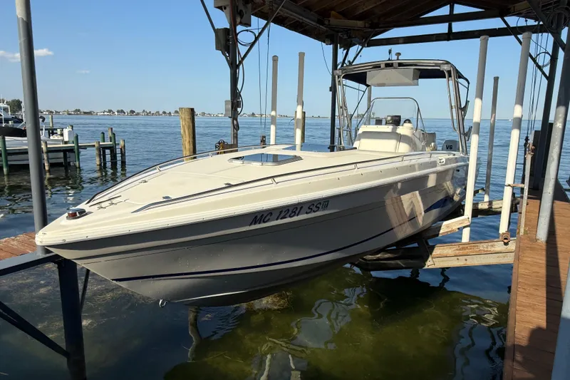 Slide: The Image of 1995 Wellcraft Scarab Sport 302 boat docked on a lift by the water. - 1