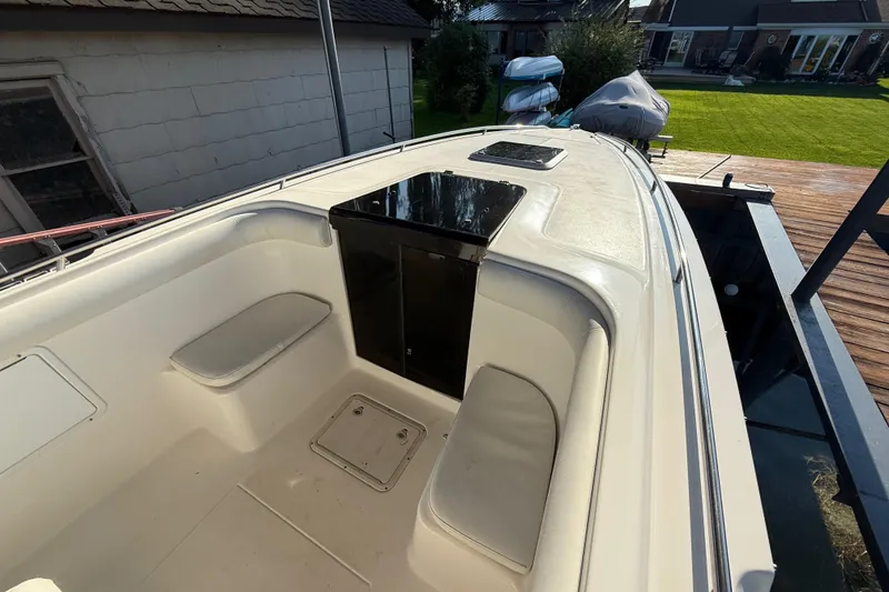 Slide: The Image of 1995 Wellcraft Scarab Sport 302 boat interior, featuring seating and storage, docked near a house. - 14