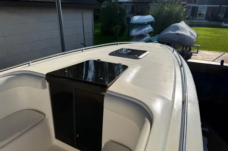 Slide: The Image of 1995 Wellcraft Scarab Sport 302 boat docked, showcasing sleek deck design and storage compartment. - 17