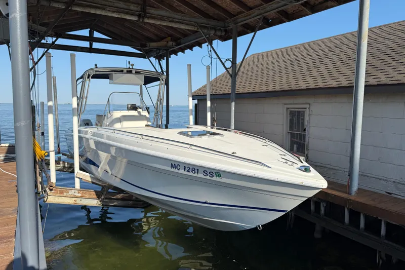 Slide: The Image of 1995 Wellcraft Scarab Sport 302 boat docked under a wooden shelter by the water. - 2