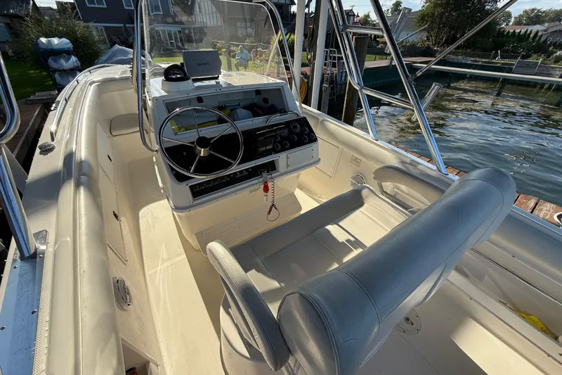 Slide: The Image of 1995 Wellcraft Scarab Sport 302 boat interior with steering wheel and seating, docked by the water. - 6