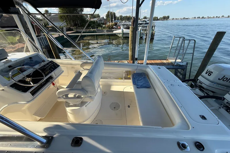 Slide: The Image of 1995 Wellcraft Scarab Sport 302 boat interior with steering console and seating, docked by the water. - 9