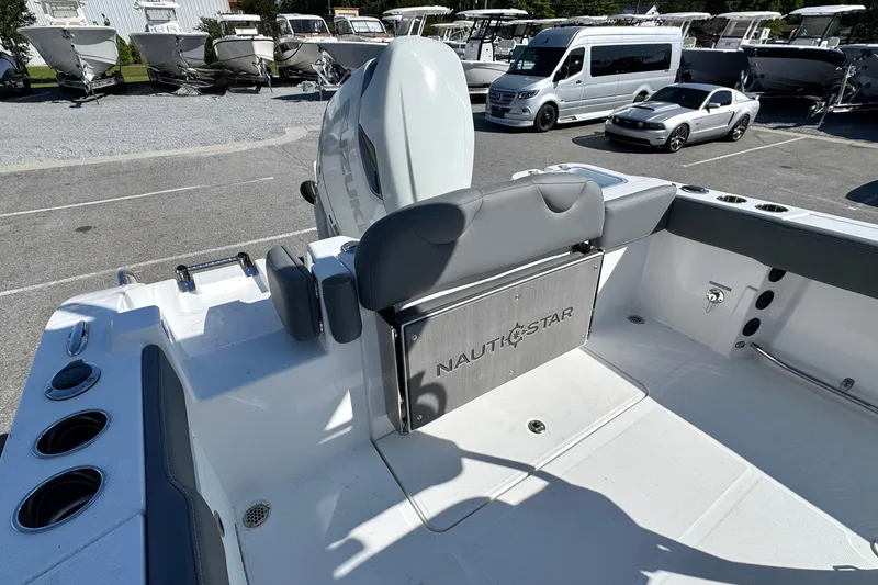 Slide: The Image of 2026 NauticStar 242 Offshore boat interior with seating and motor, parked in a marina. - 17