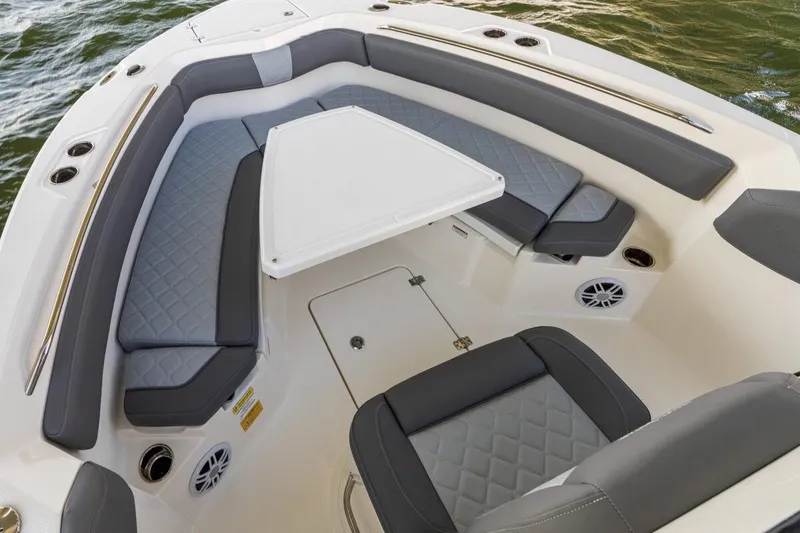 Slide: The Image of 2026 NauticStar 251 Hybrid boat interior with gray cushioned seating and table on water. - 4