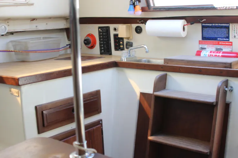 Slide: The Image of Interior of a 1980 Watkins MONOHULL sailboat kitchen with wooden cabinetry and sink. - 16