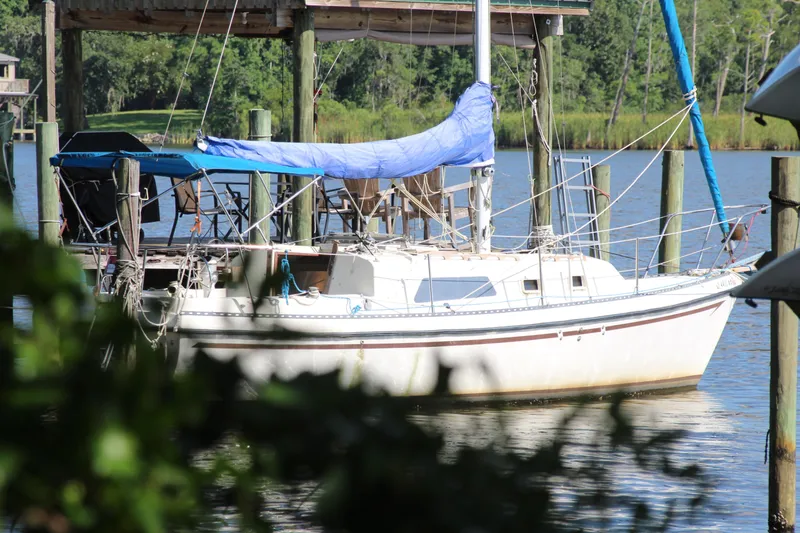 Slide: The Image of 1980 Watkins MONOHULL sailboat docked by a serene riverside with lush greenery. - 24