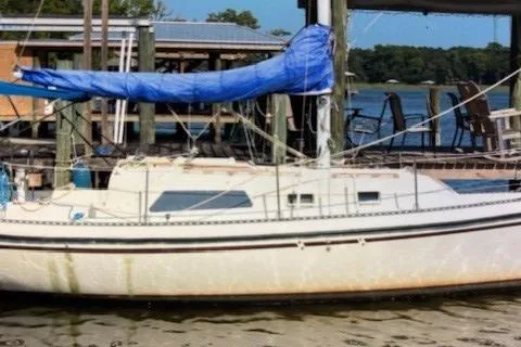 Slide: The Image of 1980 Watkins MONOHULL sailboat docked by the water with blue tarp cover. - 3