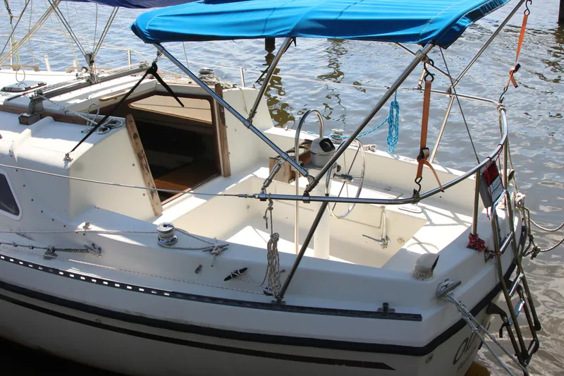 Slide: The Image of 1980 Watkins MONOHULL sailboat with blue canopy, docked on calm water. - 7
