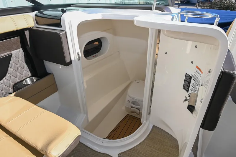 Slide: The Image of 2020 Sea Ray SLX 250 boat interior with open door to compact restroom. - 25